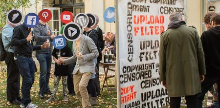 Menschen, die sich ein Schild mit den Logos bekannter Sozialer Medien vor das Gesicht halten.