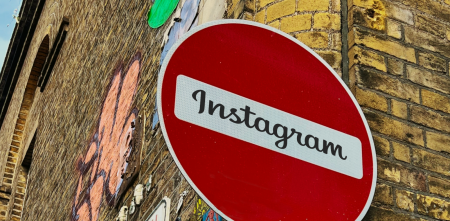 Detailaufnahme des Straßenschildes „Keine Durchfahrt“ (roter Kreis mit weißem Querbalken). Im weißen Bereich steht: „Instagram“. Im Hintergrund eine Klinkerwand mit Graffiti.