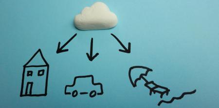 Eine Gummibärchen-Wolke schwebt über handgezeichnetem Haus, Auto und einer Sonnenliege.