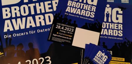 Verschiedene Werbeflyer und -plakate für die BigBrotherAwards 2023 auf einem Haufen drapiert.