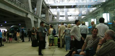 Viele Personenwarten vor einem Flughafenterminal.