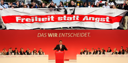 Collage: Banner zu „Freiheit statt Angst“ (oben). Sigmar Gabriel an einem Redepult während einer Veranstaltung der SPD (unten).